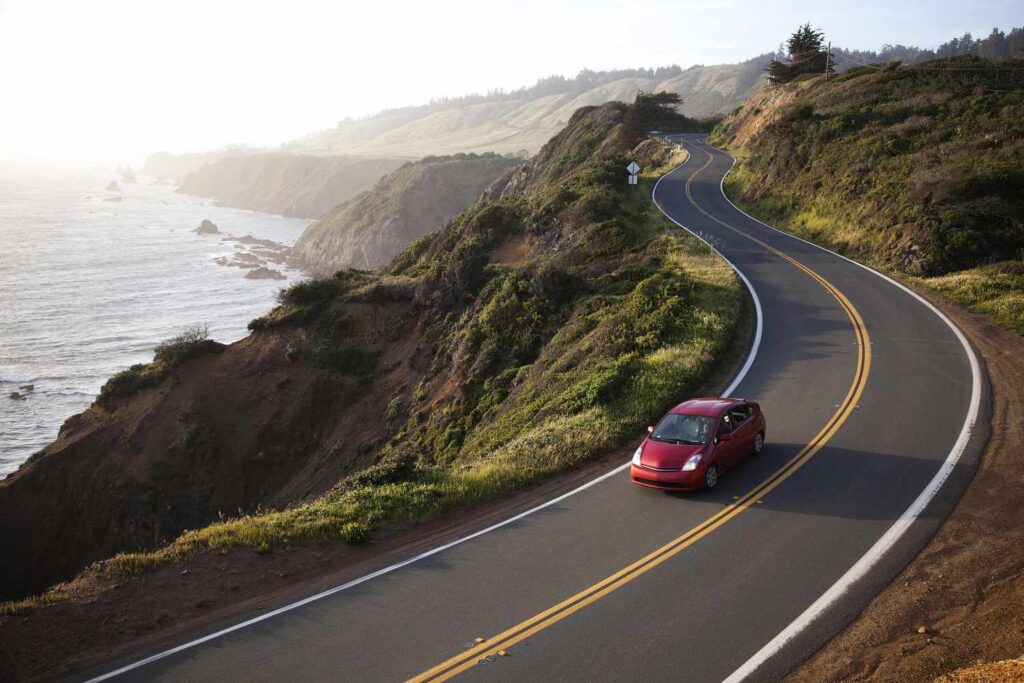 a red car drives on a highway near the ocean 113218541 58c6f1515f9b58af5c887575