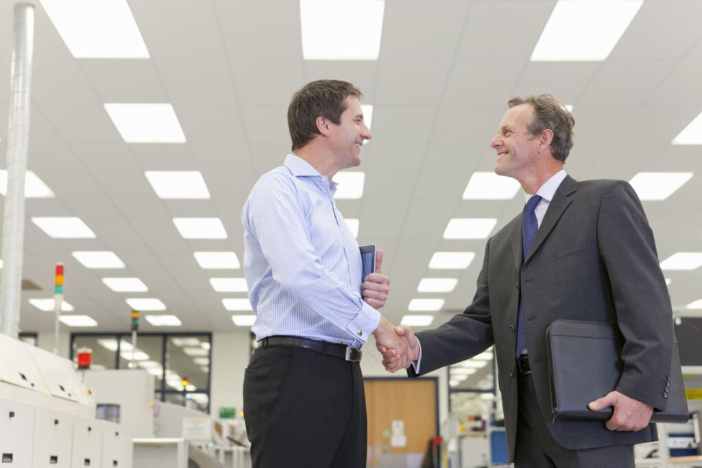businessmen shaking hands in factory 56a437a15f9b58b7d0d5e679
