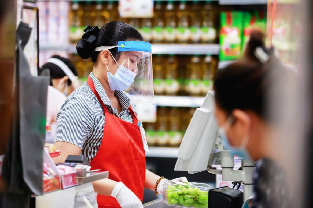 female supermarket cashier in medical protective mask working at supermarket 1220095652 7e266d87cc76