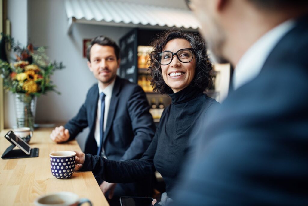 group of three business people sitting at a coffee shop 1129377233 196e76cb58c540adb6641292938aff37