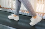 motion of runner woman feet running on machine treadmill at fitness gym center or health club with s