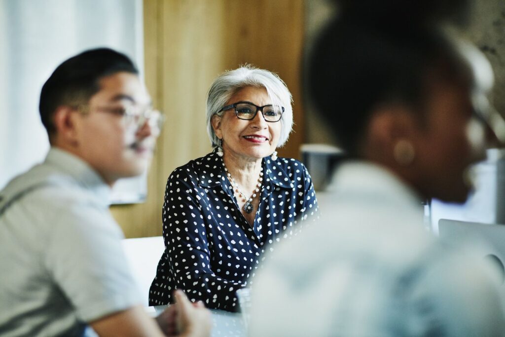 smiling mature female business owner listening during presentation during meeting in office conferen