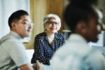 smiling mature female business owner listening during presentation during meeting in office conferen